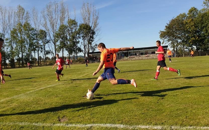 Mecz piłkarski na zielonym boisku, zawodnicy w akcji.