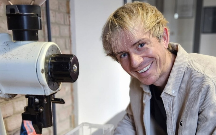 Mężczyzna uśmiechający się przy maszynie do mielenia.