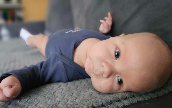 Noworodek leży na kanapie, patrząc w obiektyw.