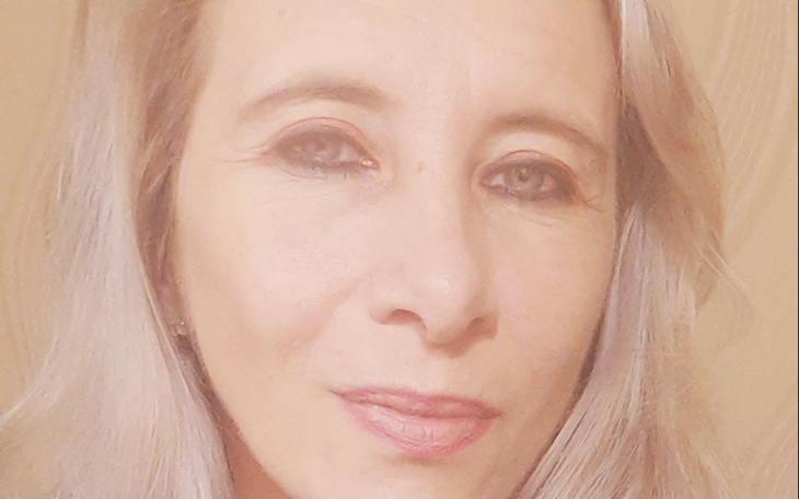 Portret kobiety z jasnymi włosami i delikatnym uśmiechem.