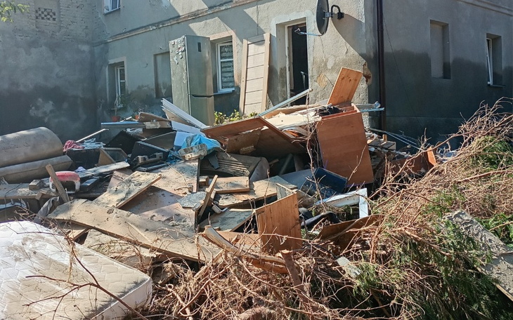 Zniszczony teren z gruzem i odpadami budowlanymi.