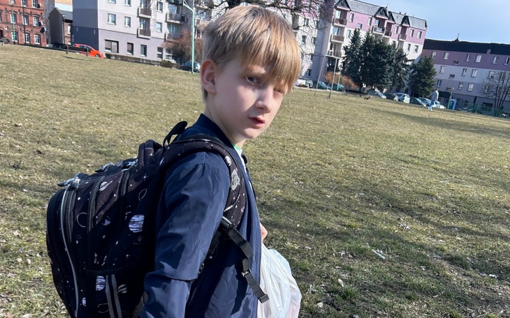 Chłopiec spacerujący po parku z plecakiem.