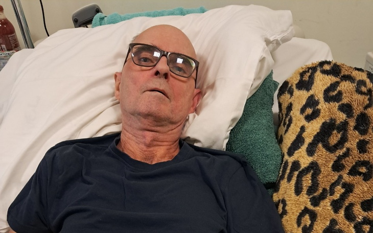 Mężczyzna leżący na łóżku w okularach.