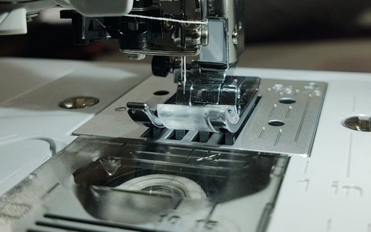 Zbliżenie na maszynę do szycia w trakcie pracy.