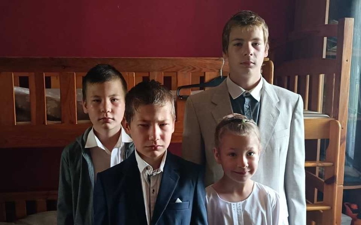 Czwórka dzieci w eleganckich strojach, pozująca do zdjęcia.