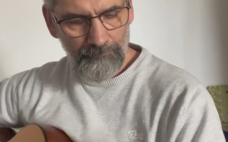 Mężczyzna grający na gitarze, skupiony na muzyce.