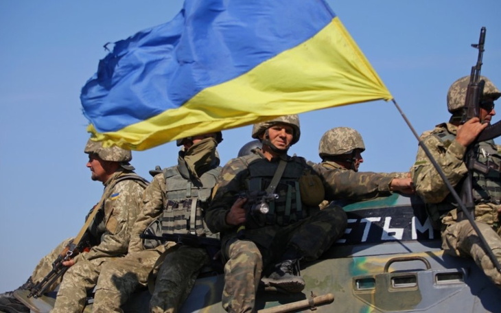 Ukraińscy żołnierze na pojeździe wojskowym z flagą.