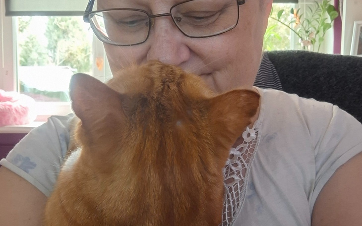 Kobieta z rudym kotem, przytulają się w przytulnym otoczeniu.