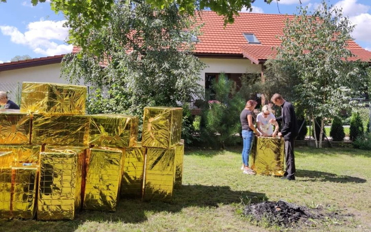 Dzieci bawią się z dużymi złotymi paczkami na trawie.