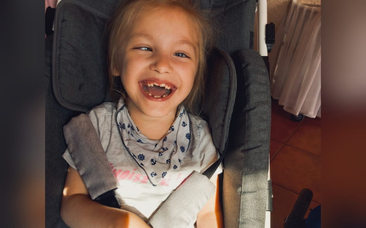 Uśmiechnięta dziewczynka w wózku, cieszy się chwilą.