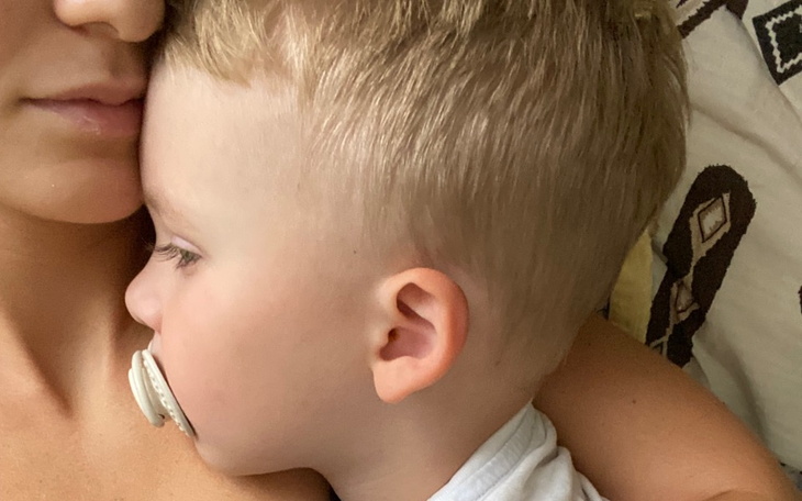 Dziecko przytulone do matki, trzymające smoczek.