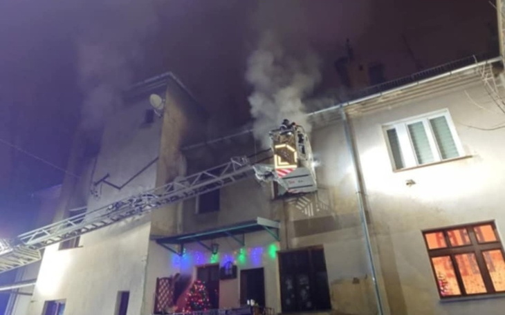 Strażacy gaszący pożar w budynku, dym unosi się w powietrzu.