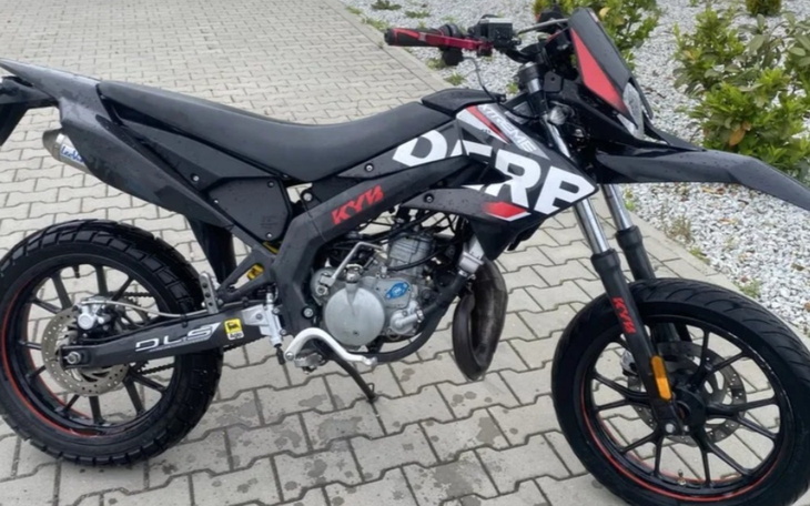Motocykl terenowy zaparkowany na chodniku.