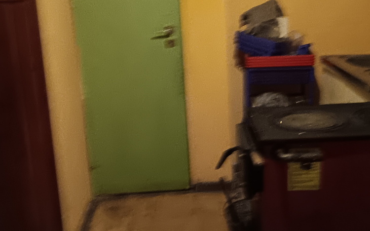 Zielone drzwi w kuchni, z widocznymi przedmiotami w tle.