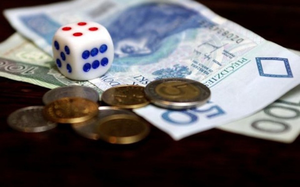 
        Monety i kostka do gry na banknotach w polskich złotych.
    