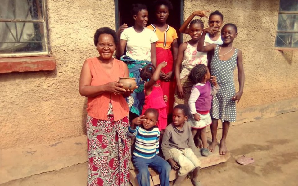 Grupa dzieci i dorosłych pozujących przed domem.