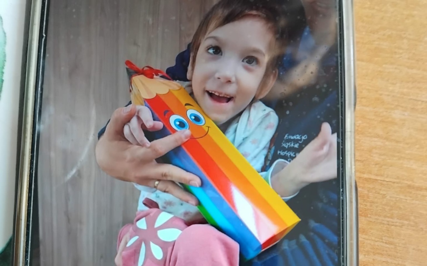 
        Dziecko trzyma kolorowy prezent w kształcie kredki.
    