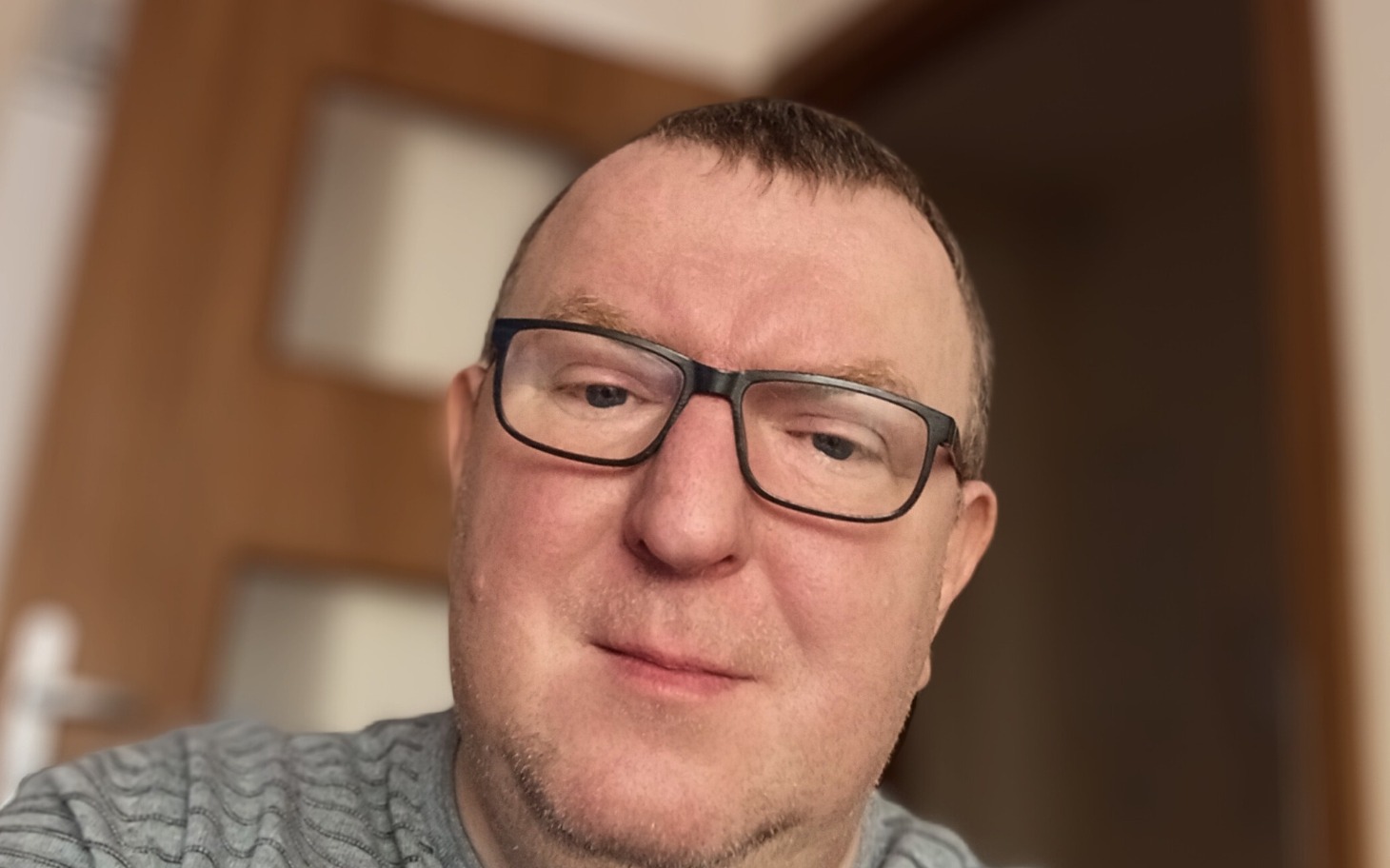 
        Mężczyzna w okularach, uśmiechający się do kamery.
    
