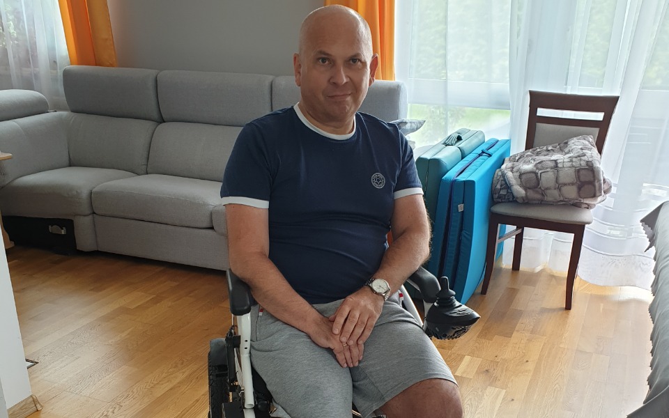 
        Mężczyzna na wózku inwalidzkim, siedzący w jasnym pomieszczeniu.
    