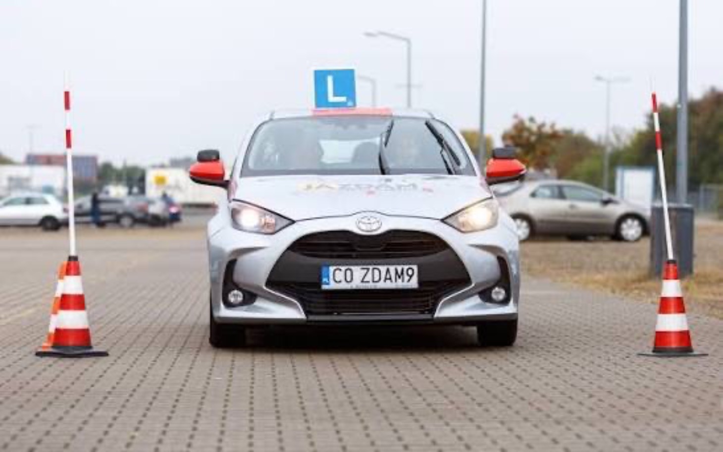 
        Samochód do nauki jazdy z oznaczeniem L, przygotowany do manewrów.
    