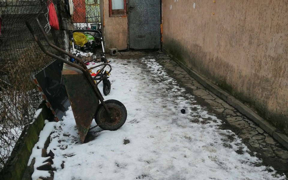 
        Zimowy widok na podwórko z wózkiem i narzędziami.
    
