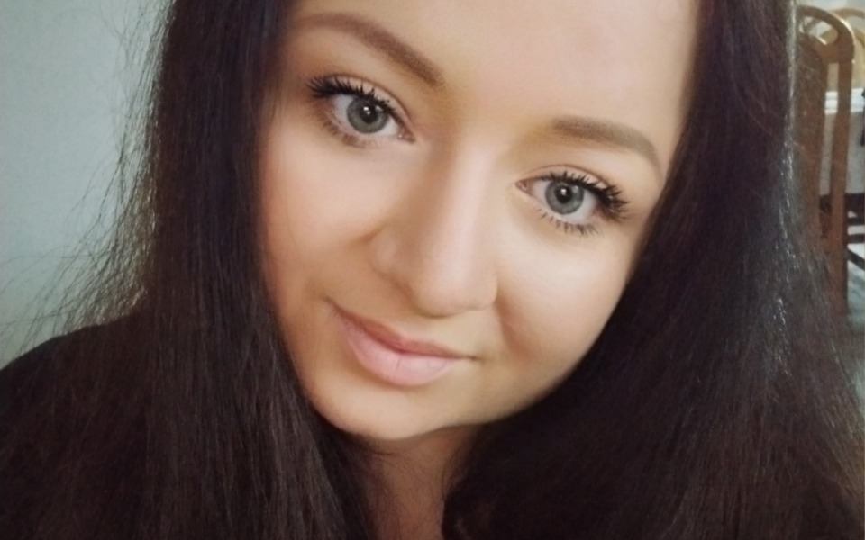 
        Portret uśmiechniętej kobiety z długimi włosami.
    