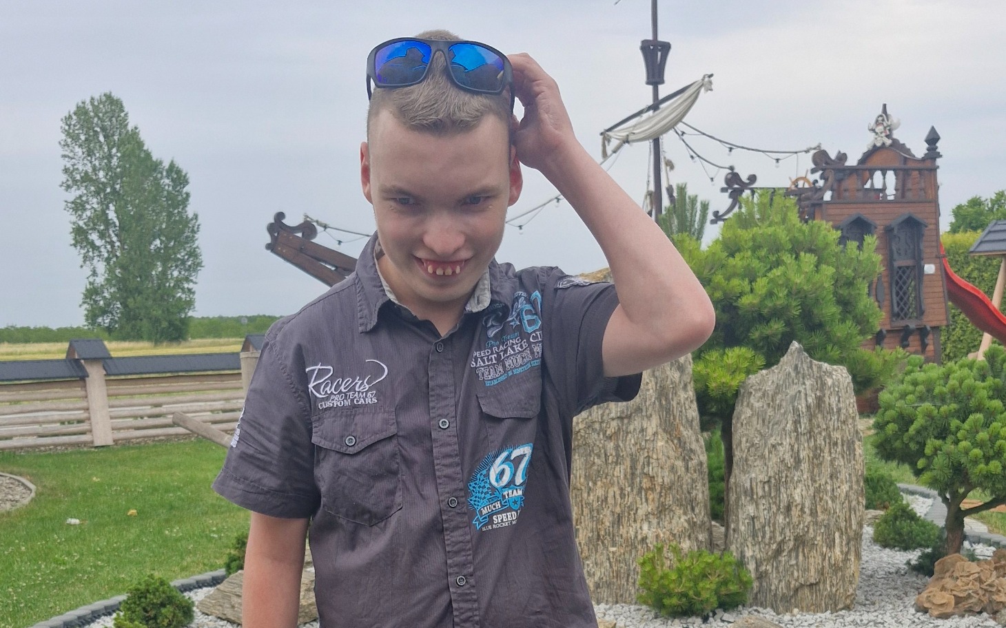 
        Młody mężczyzna z okularami przeciwsłonecznymi, uśmiechnięty.
    