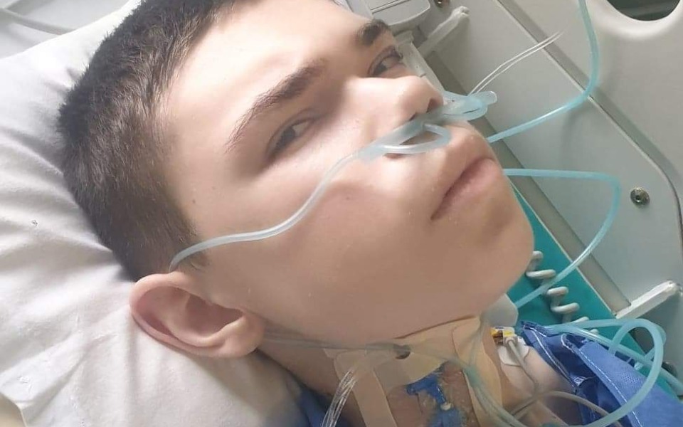 
        Chłopak w szpitalu, z rurkami tlenowymi i monitorami medycznymi.
    