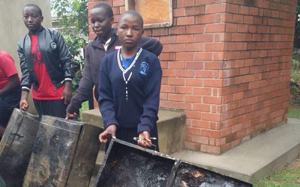 
        Dzieci niosące zniszczone skrzynie, skupione na zadaniu.
    