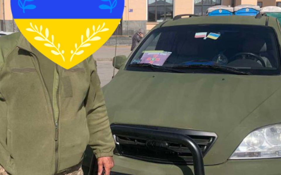 
        Mężczyzna w mundurze obok pojazdu, symbol wsparcia.
    