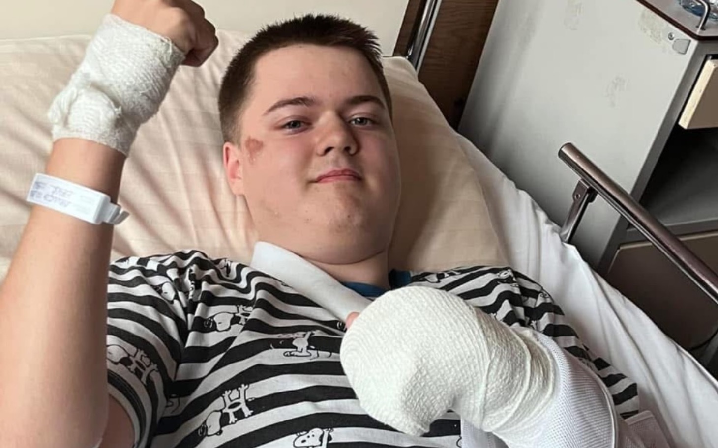 
        Chłopak w szpitalu z opatrunkami na rękach, uśmiechający się.
    