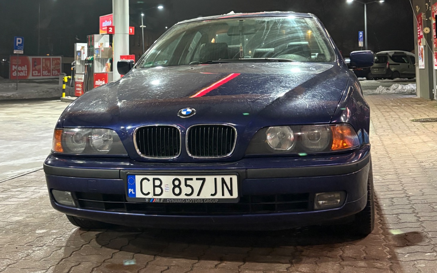 
        Samochód marki BMW zaparkowany na stacji benzynowej.
    