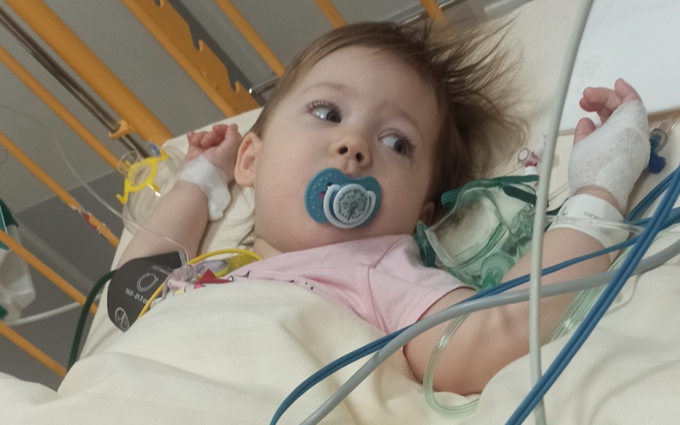 
        Mała dziewczynka w szpitalu, z rurkami i smoczkiem w ustach.
    