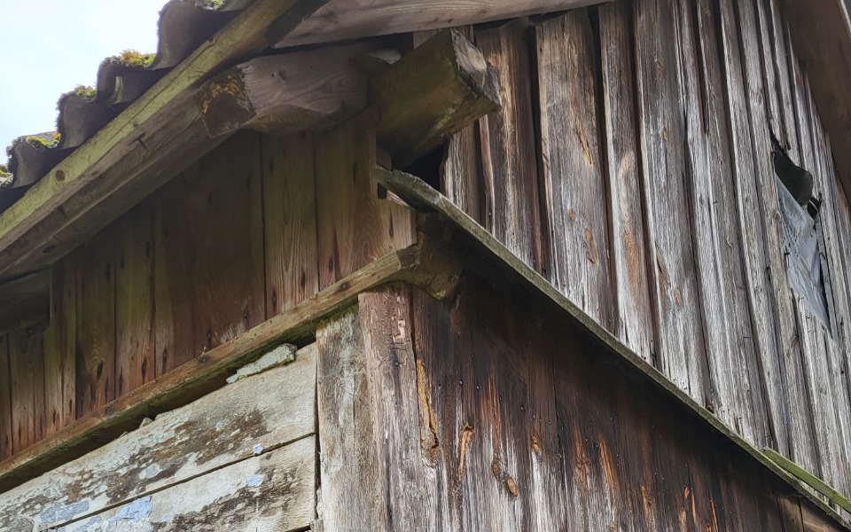 
        Fragment drewnianej chaty, z widocznymi śladami upływu czasu.
    