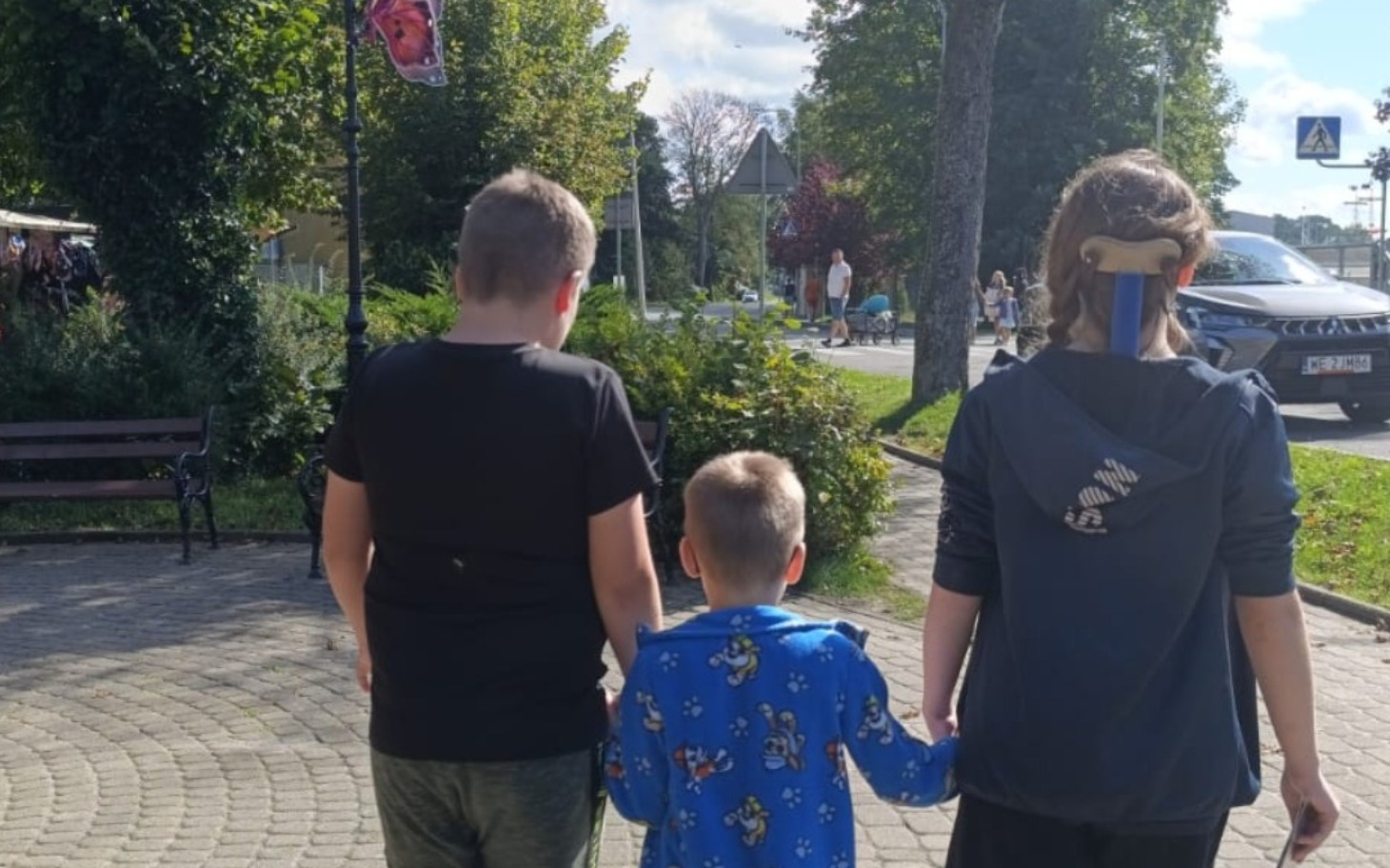 
        Dzieci spacerujące razem, trzymające się za ręce.
    