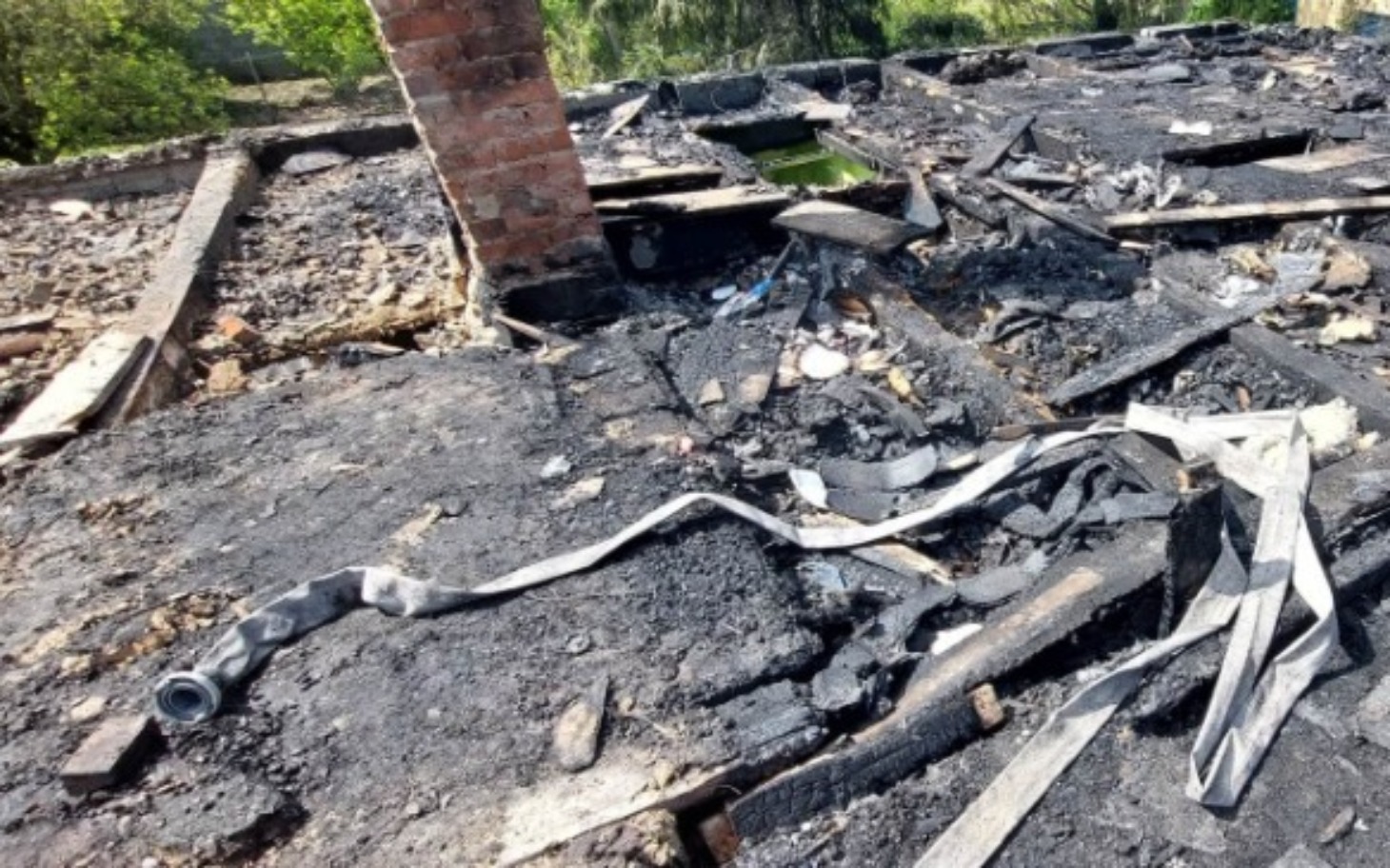 
        Zniszczony dach budynku po pożarze, z pozostałościami materiałów.
    