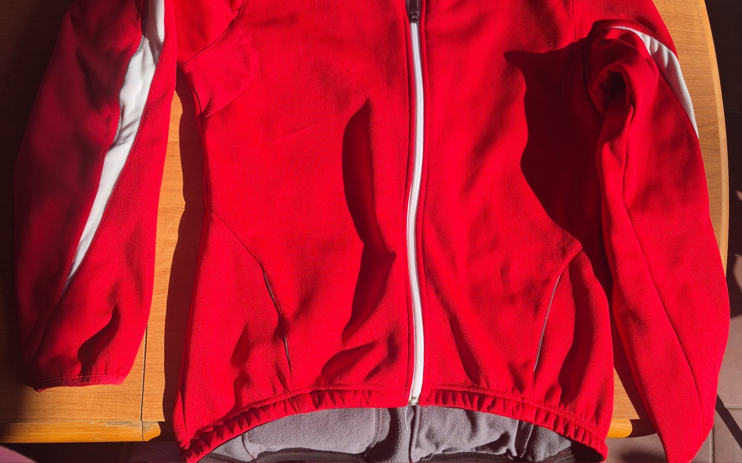 
        Czerwona kurtka rozłożona na stole.
    