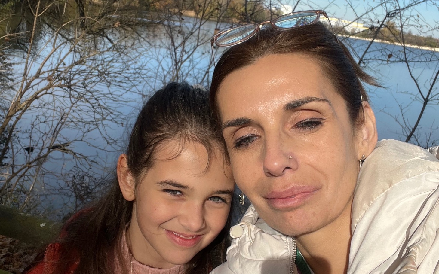 
        Mama z córką na tle jeziora, uśmiechnięte i szczęśliwe.
    