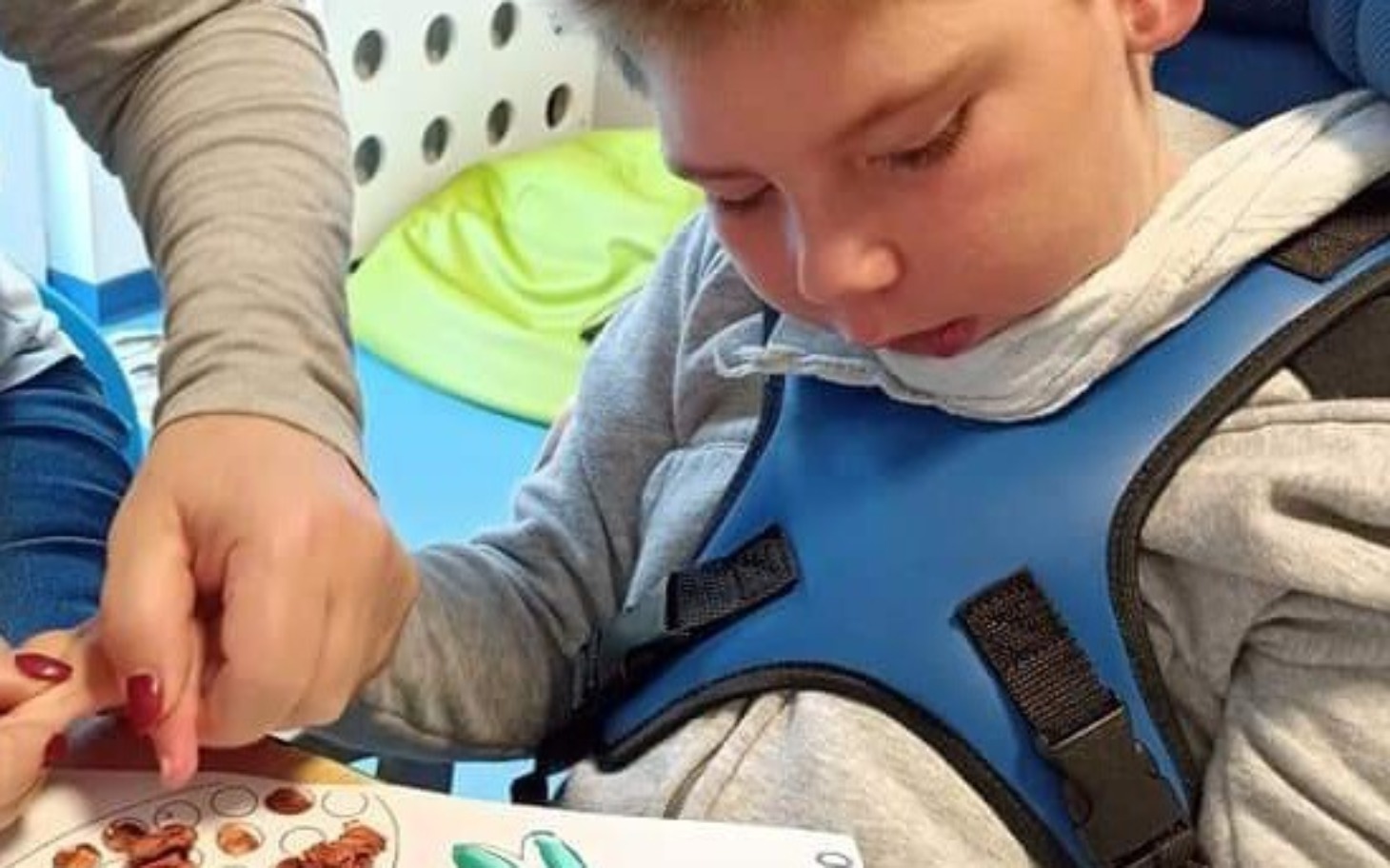 
        Chłopiec podczas zajęć terapeutycznych, skupiony na pracy.
    