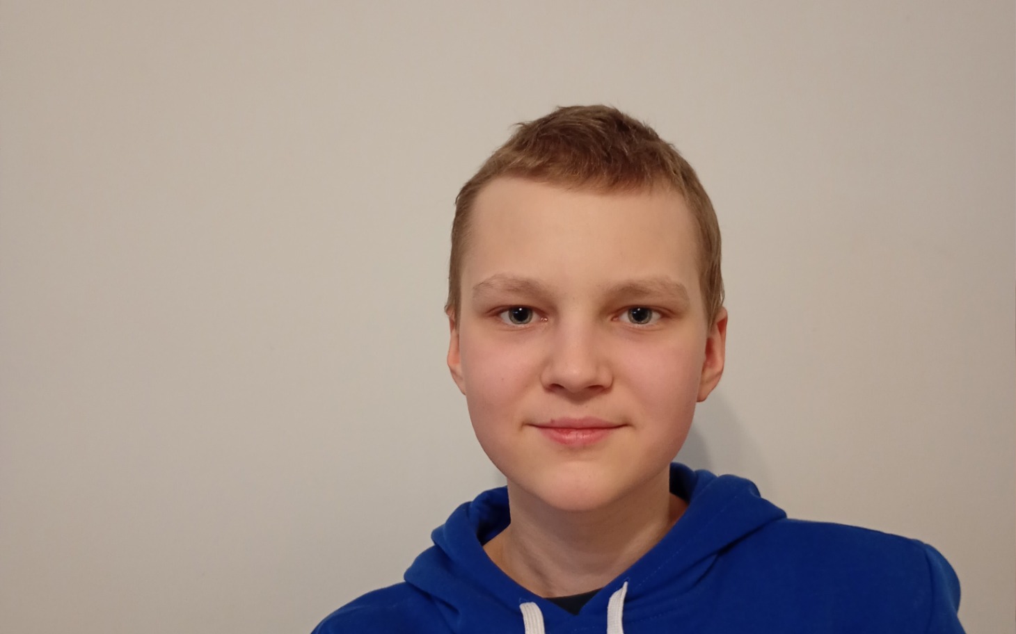 
        Chłopiec w niebieskiej bluzie, patrzący w kamerę.
    