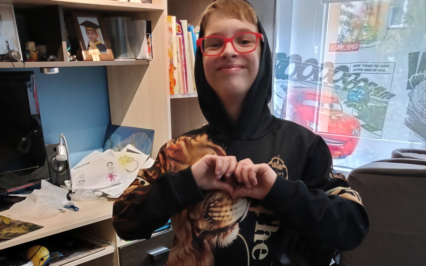 
        Chłopiec w okularach robiący serce z rąk.
    