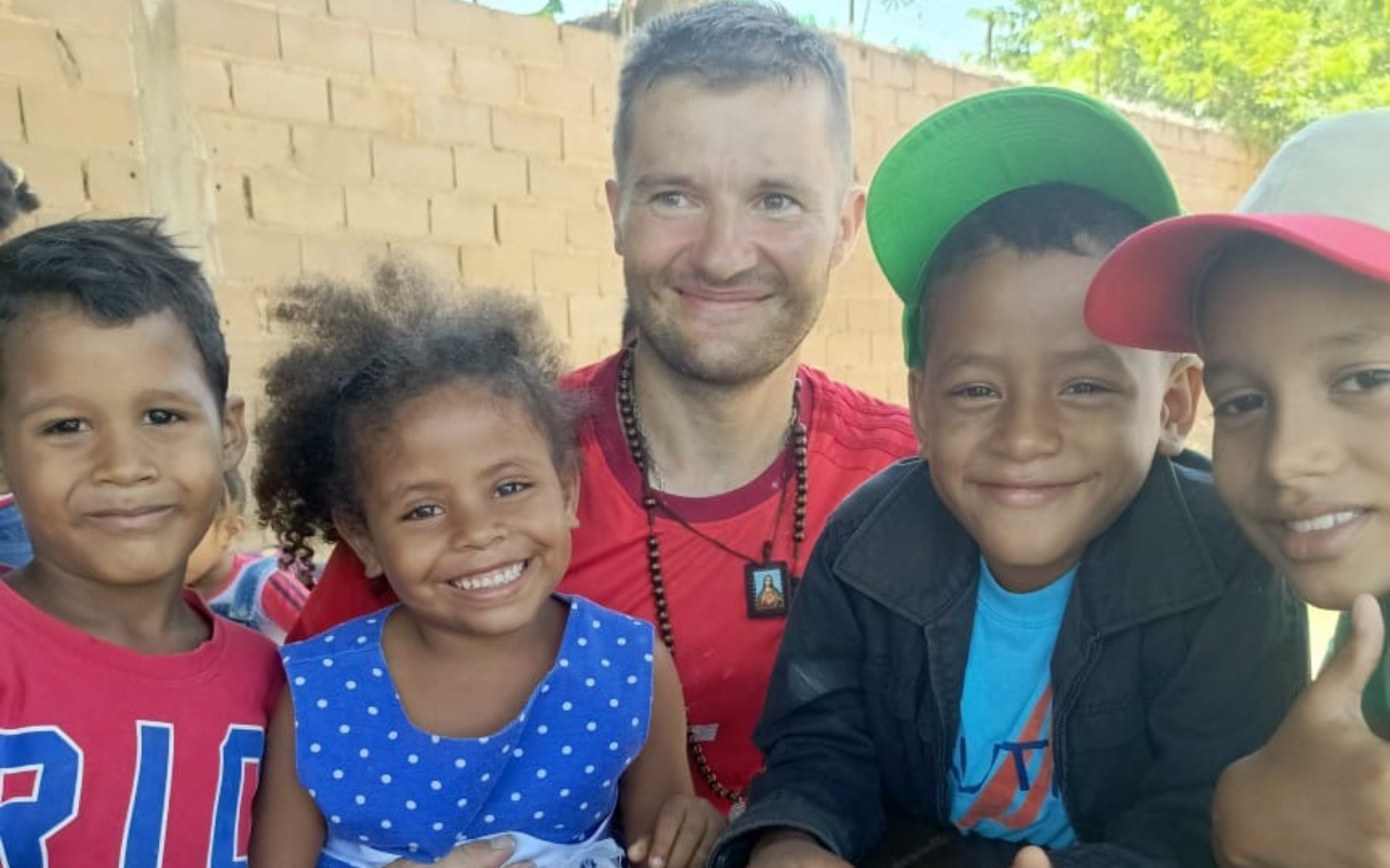 
        Grupa dzieci z uśmiechami na twarzach, spędzających czas z dorosłym.
    