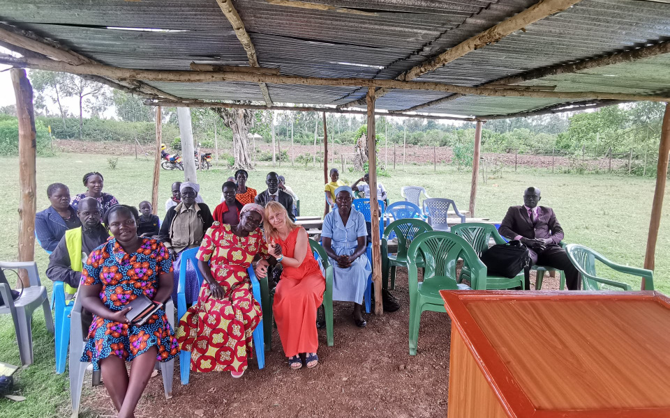 
        Grupa ludzi siedzących na zewnątrz, w różnorodnych strojach.
    