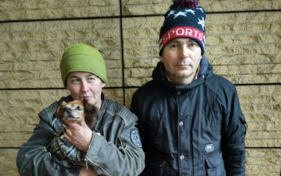 
        Para z psem na tle kamiennej ściany.
    