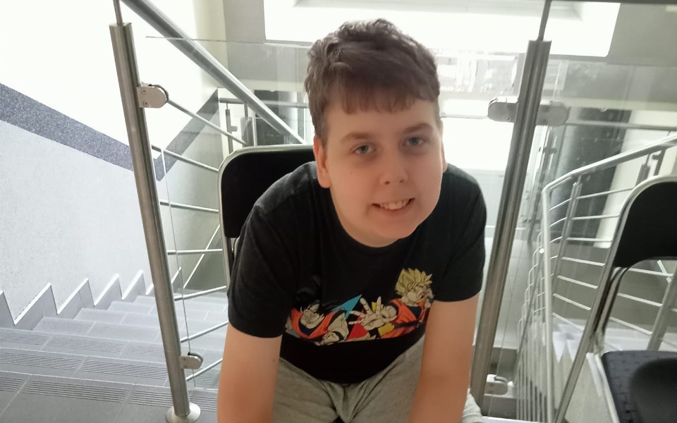 
        Chłopiec uśmiechający się na schodach, radosny moment.
    