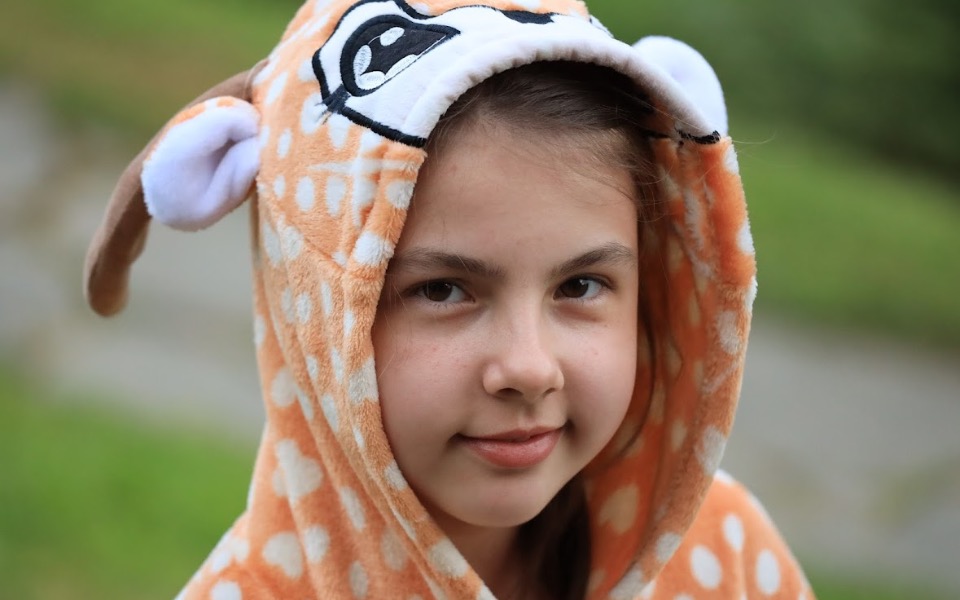 
        Dziewczynka w pomarańczowym kocie z uszami.
    