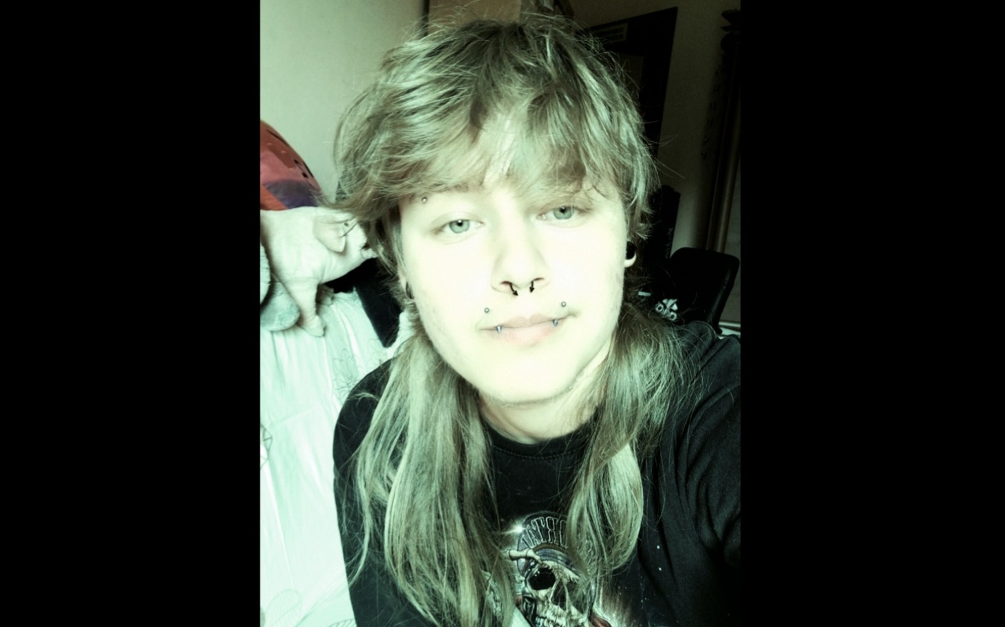 
        Młoda osoba z kolczykami, patrząca w obiektyw.
    