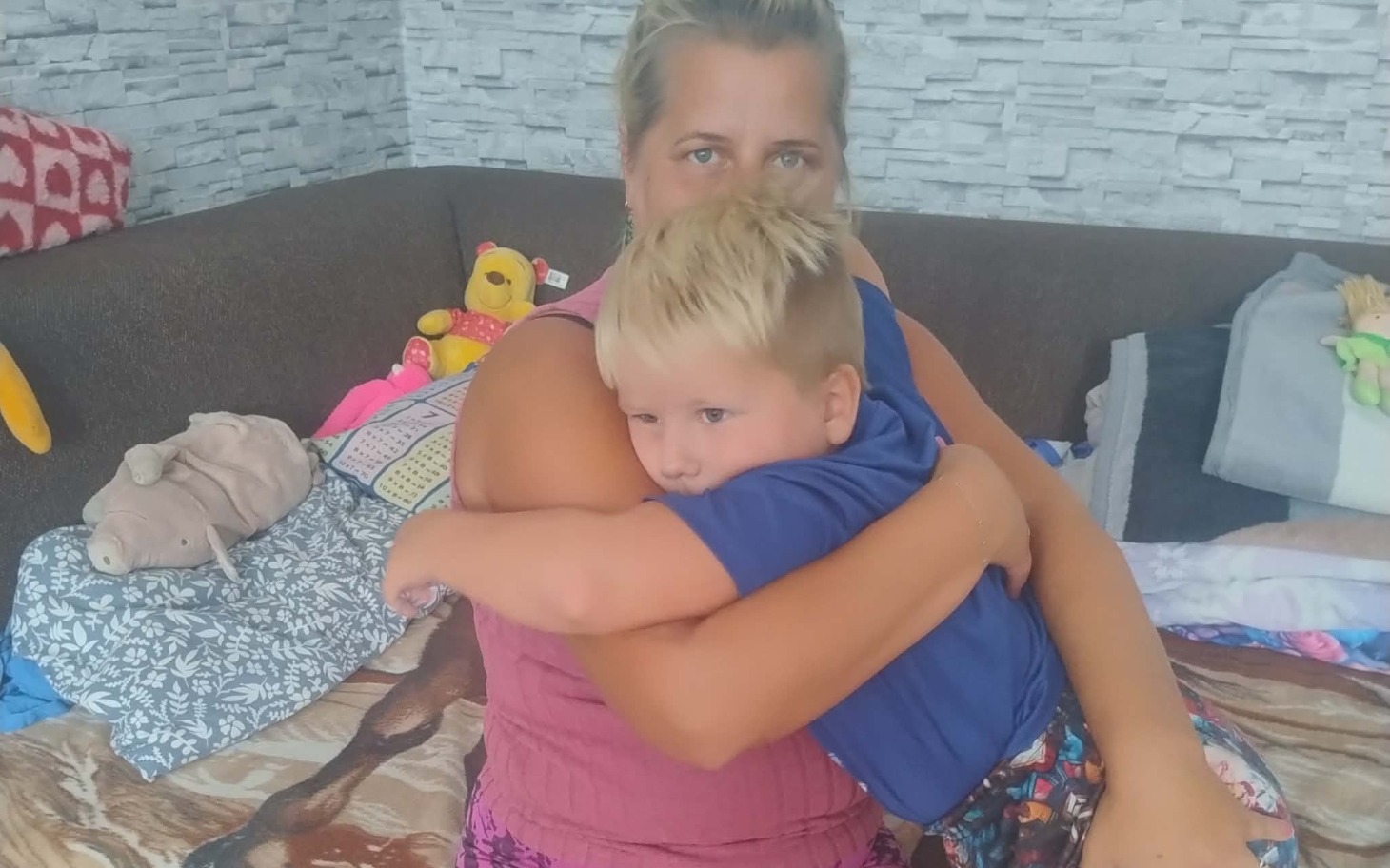 
        Kobieta trzymająca dziecko na kolanach w sali zdjęciem grupowym przy stole.
    