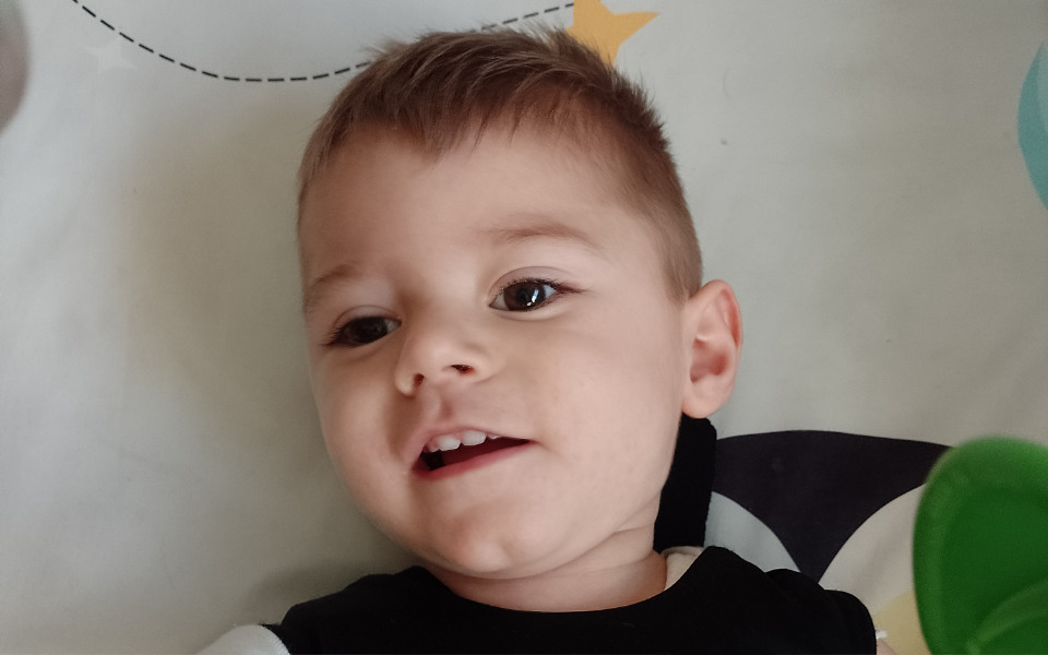 
        Mały chłopiec uśmiecha się do kamery.
    