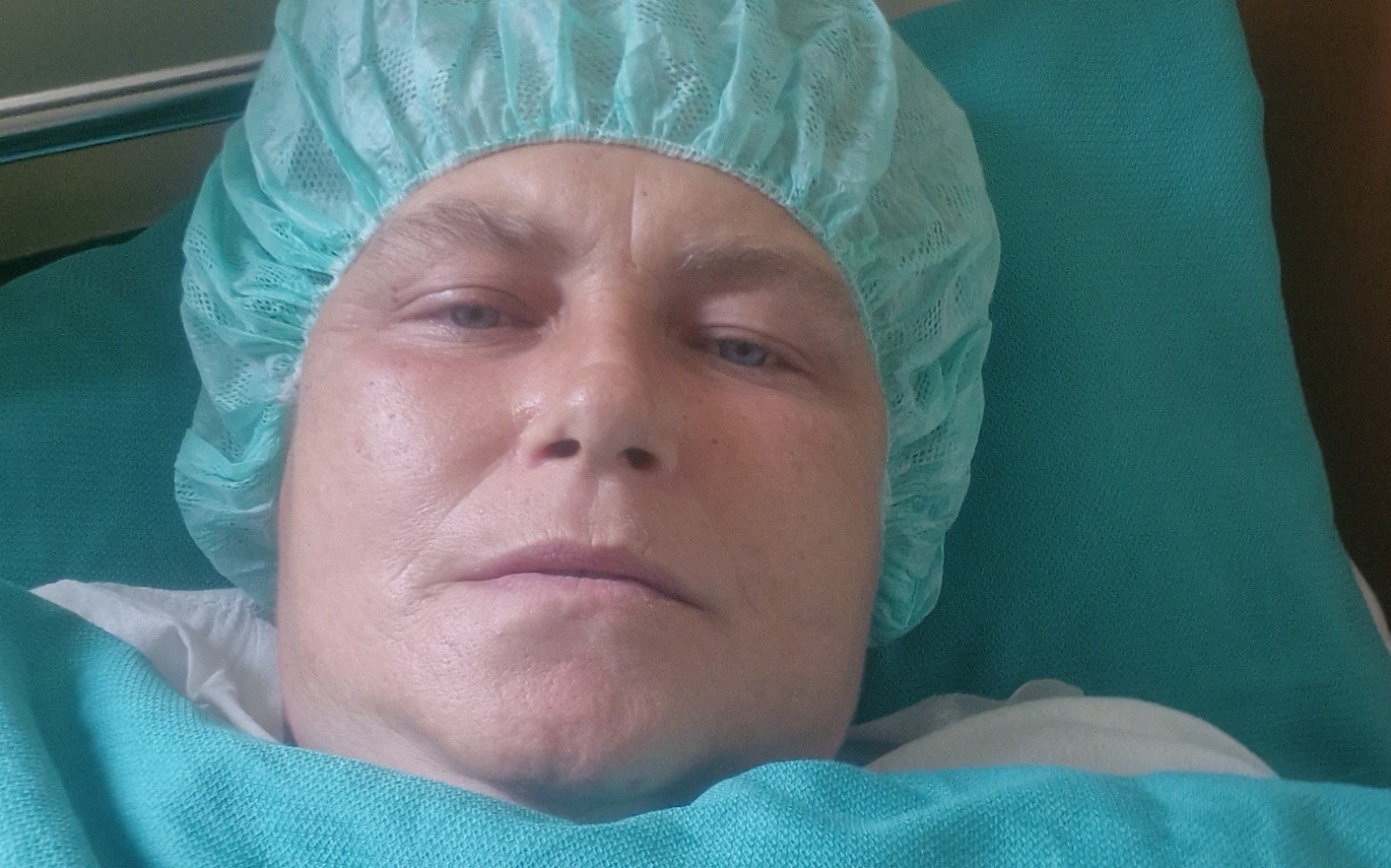 
        Osoba w szpitalu, przygotowana do zabiegu, w zielonym czepku.
    